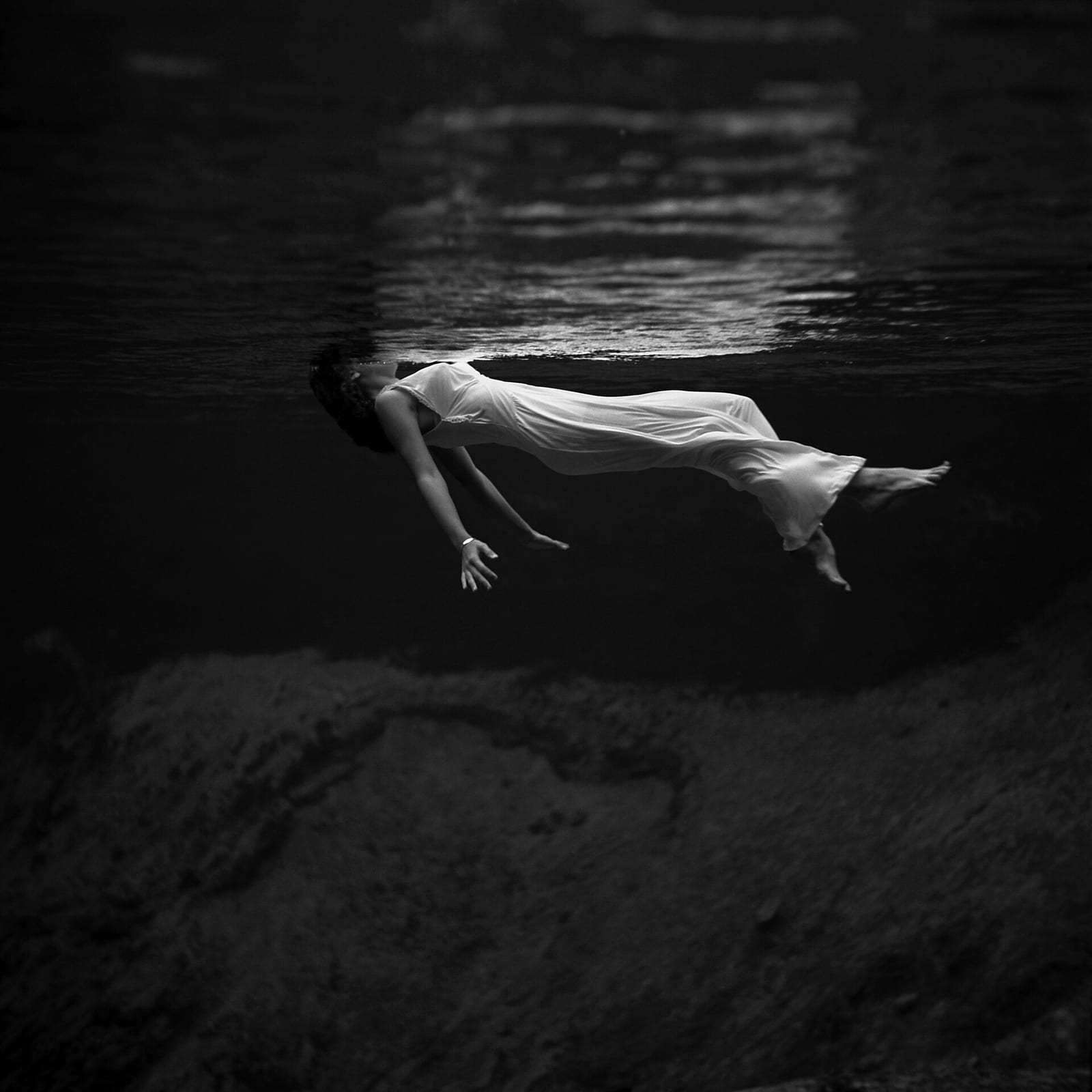 Underwater view of a woman, wearing a long gown, floating in water. Photograph by Toni Frissell at Weeki Wachee Springs , Florida , USA, 1947.