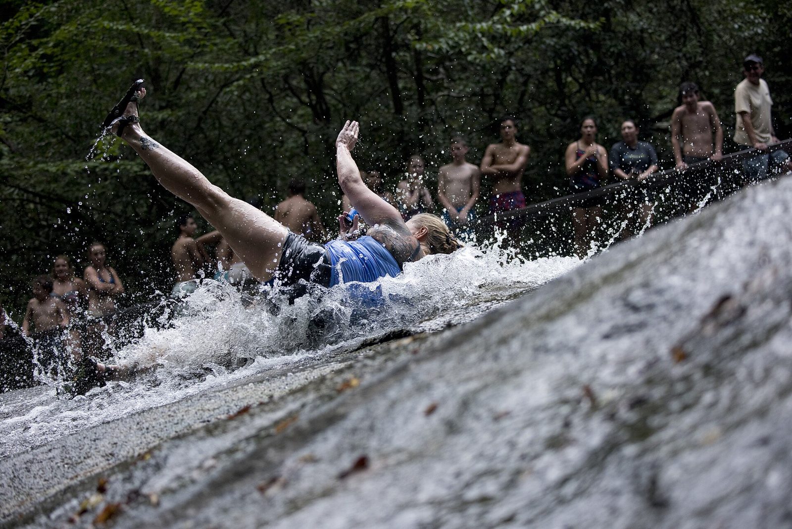 A woman slides down the famous Sliding Rock while patrons watch in line in the Pisgah National Forest, NC.  Sliding Rock is a 60-foot slippery cascade into the 