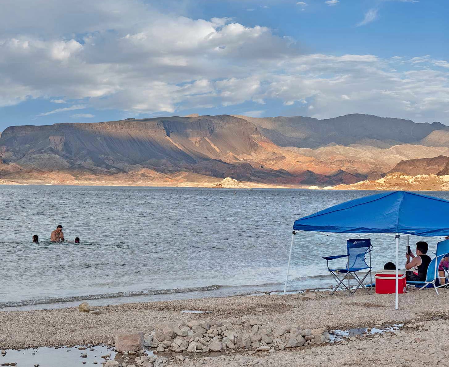 Swimmers and a shade canopy at Boulder Beach, Fortification Hill behind