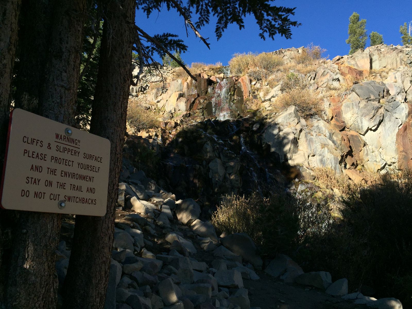 Cliffs and slippery surface warning sign below the falls on Galena Creek