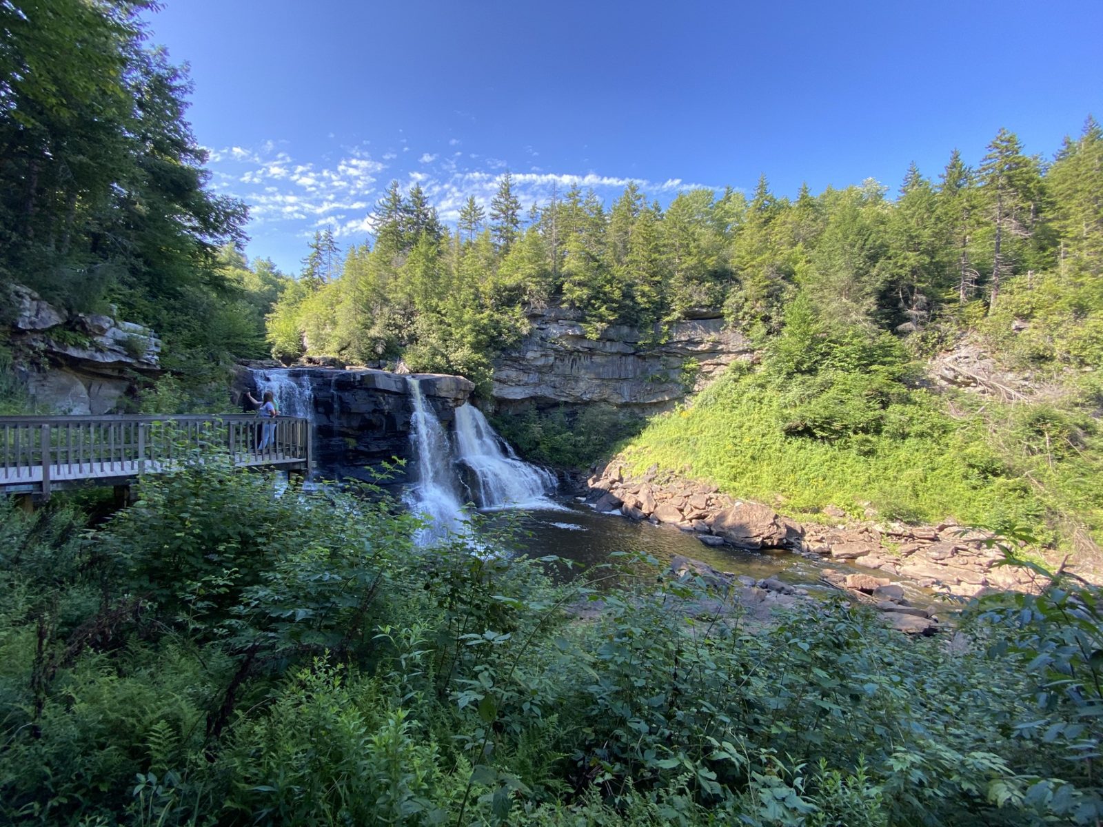 This is a photograph of the waterfalls located in Blackwater Falls State Park in West Virginia. The photo is taken from a lower viewing deck, with the higher vi