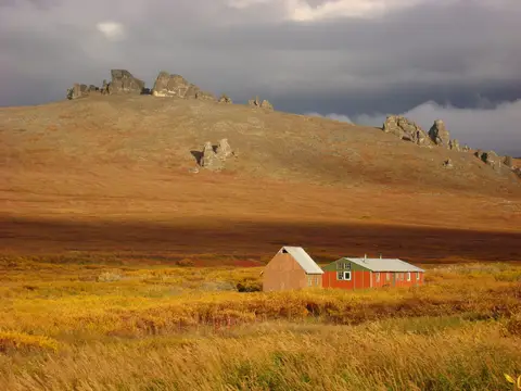 Bering Land Bridge National Preserve, Alaska. View of the bunkhouse at Serpentine Hot Springs in the rosy light of sunset in an autumn landscape.