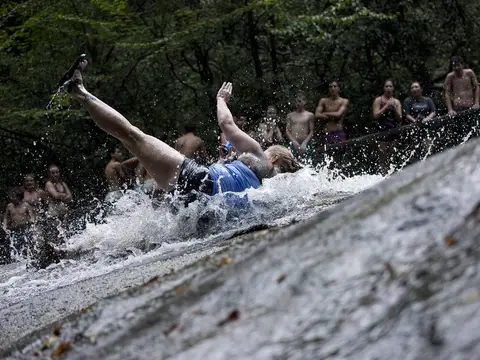 A woman slides down the famous Sliding Rock while patrons watch in line in the Pisgah National Forest, NC.  Sliding Rock is a 60-foot slippery cascade into the 