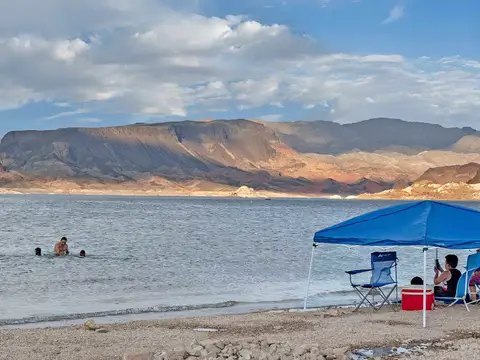Swimmers and a shade canopy at Boulder Beach, Fortification Hill behind